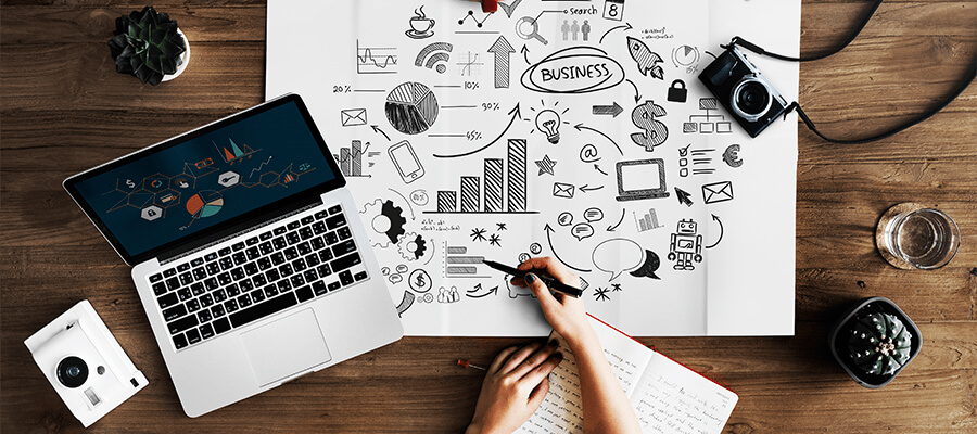 میز کار طراح وب با لپ‌تاپ، دفترچه طراحی و ترسیم ایده‌های کسب‌وکار